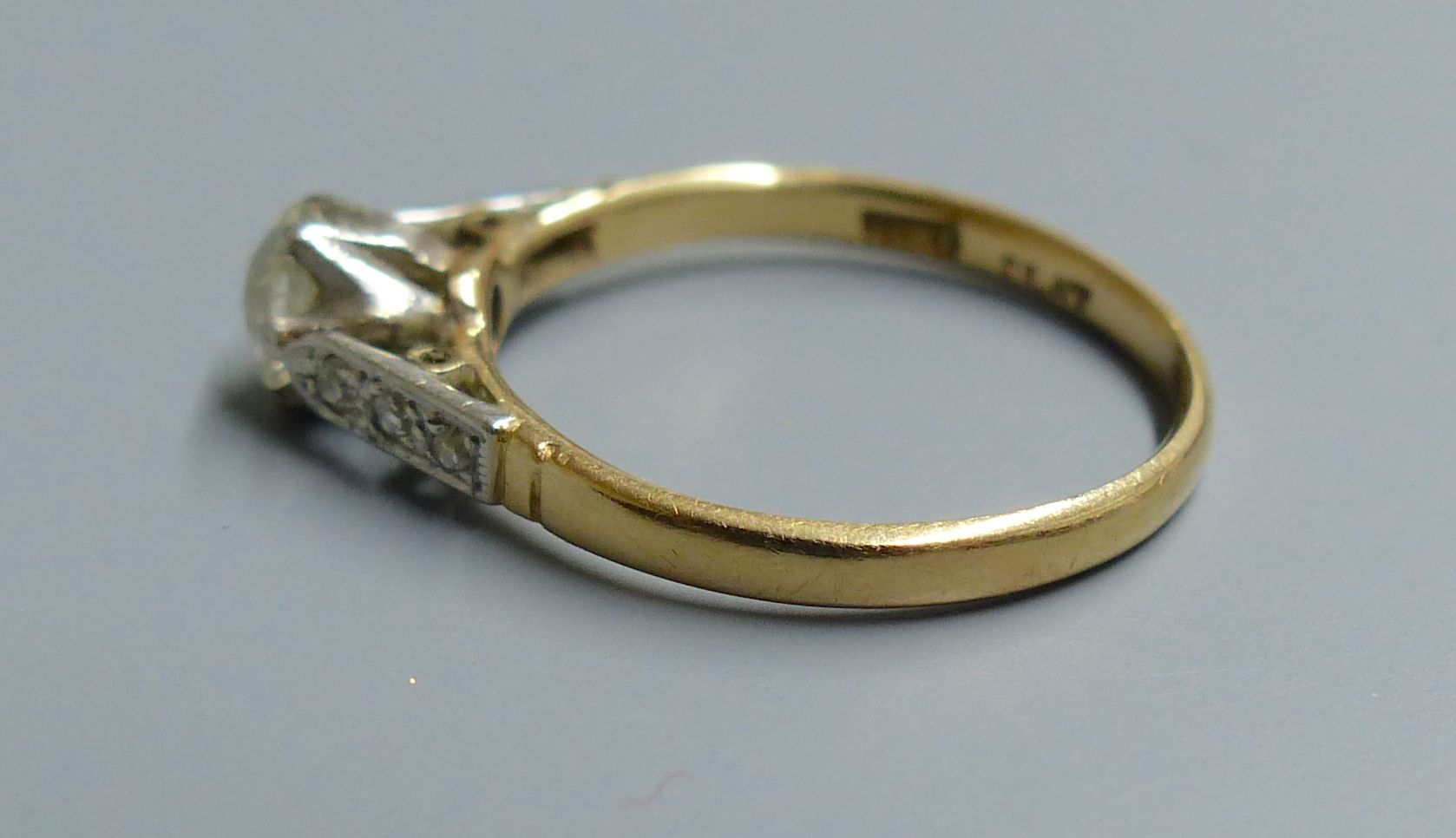 An 18ct and plat. single stone diamond ring, with diamond set shoulders, size I, gross 1.6 grams.